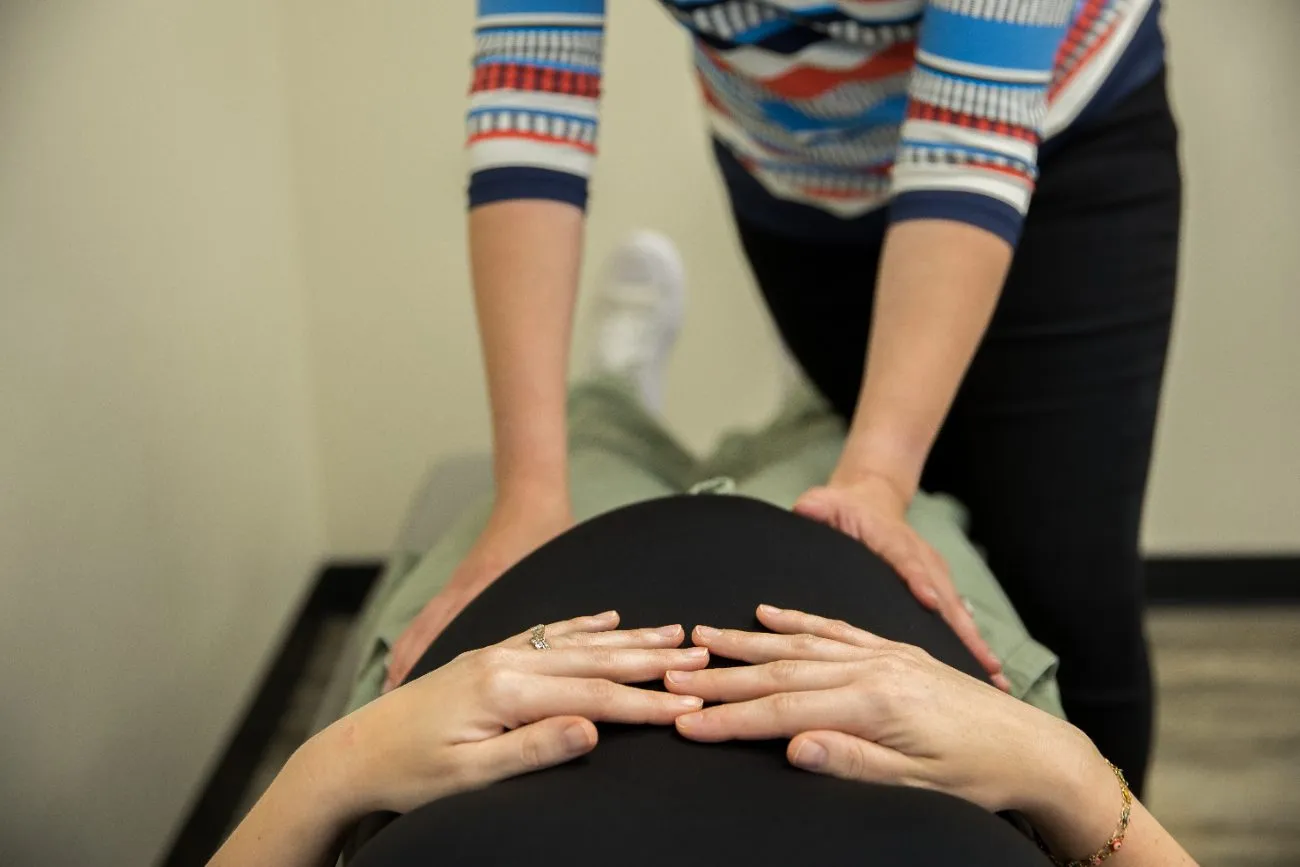 Hands resting on a pregnant belly during a gentle prenatal visit